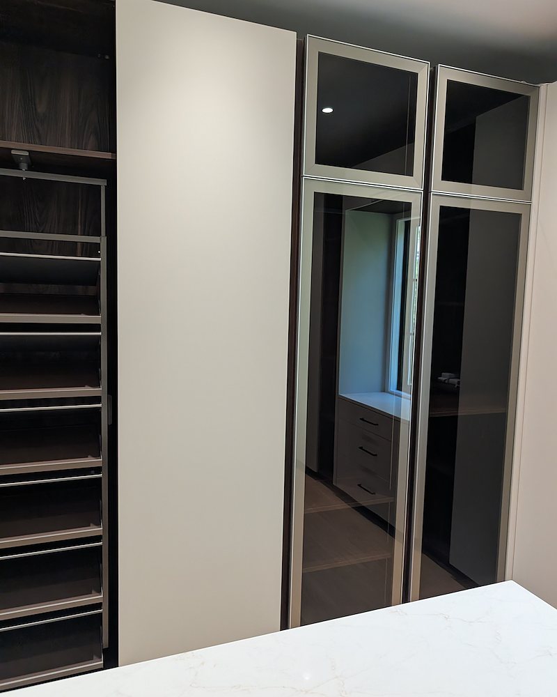 Smoke-glass wardrobe doors beside a quartz-topped base cabinet