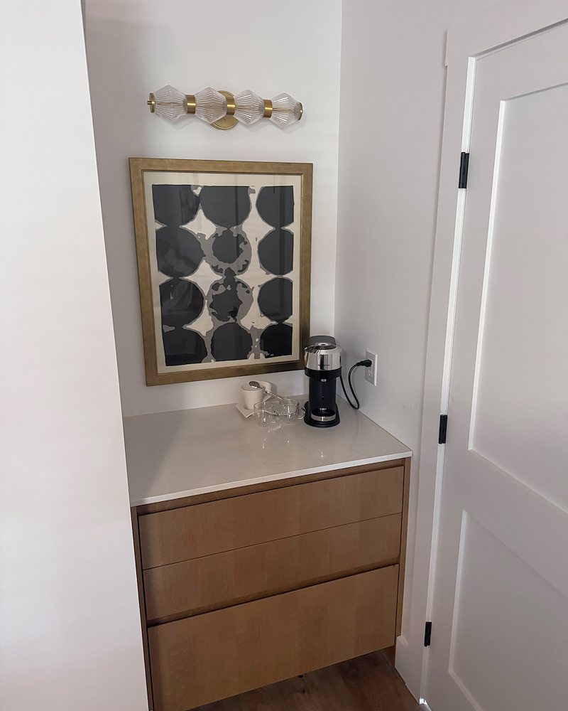 Coffee station built into a hallway nook, with three slab-front drawers in rift oak veneer and a white countertop