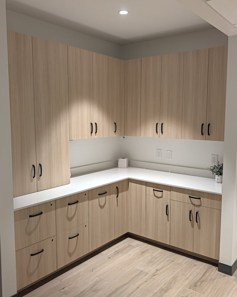 L-shaped corner run of light wood-grain laminate base and upper cabinets with a quartz top