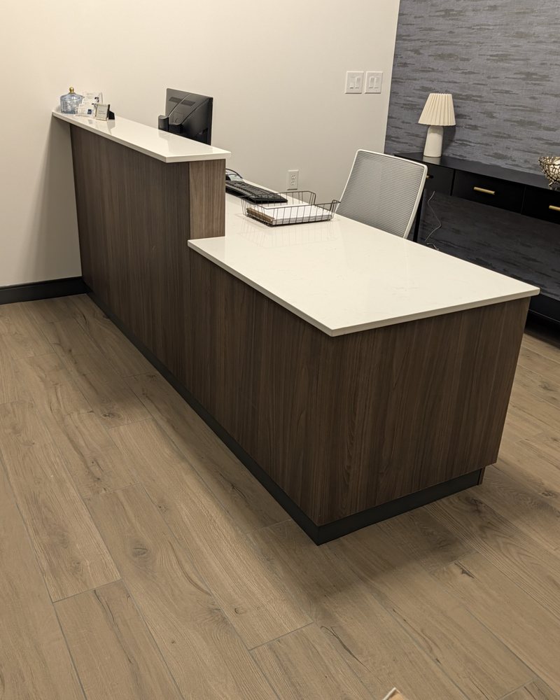 Reception desk in dark wood-grain laminate with a raised quartz transaction counter