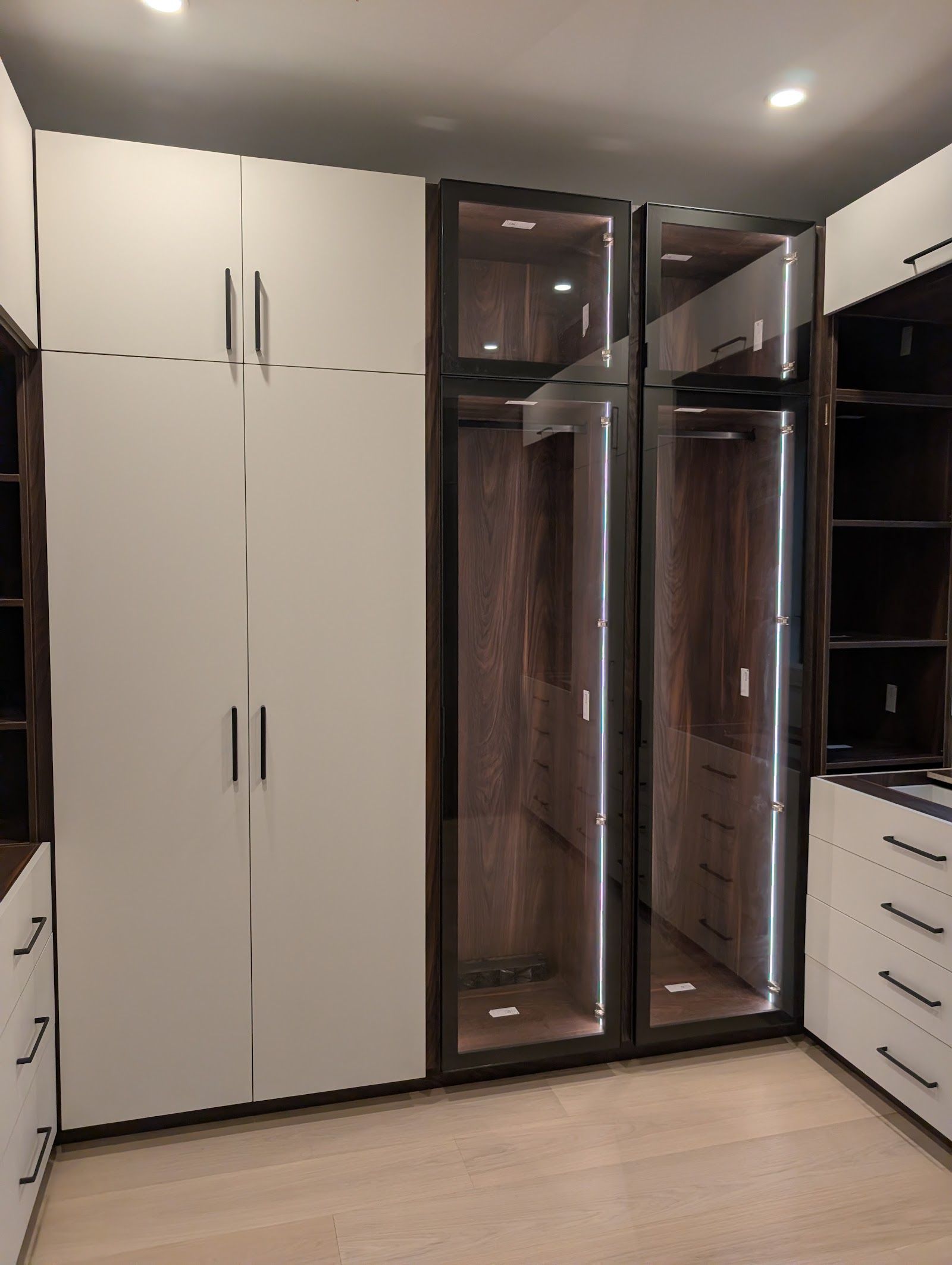Glass-front wardrobe towers with integrated lighting