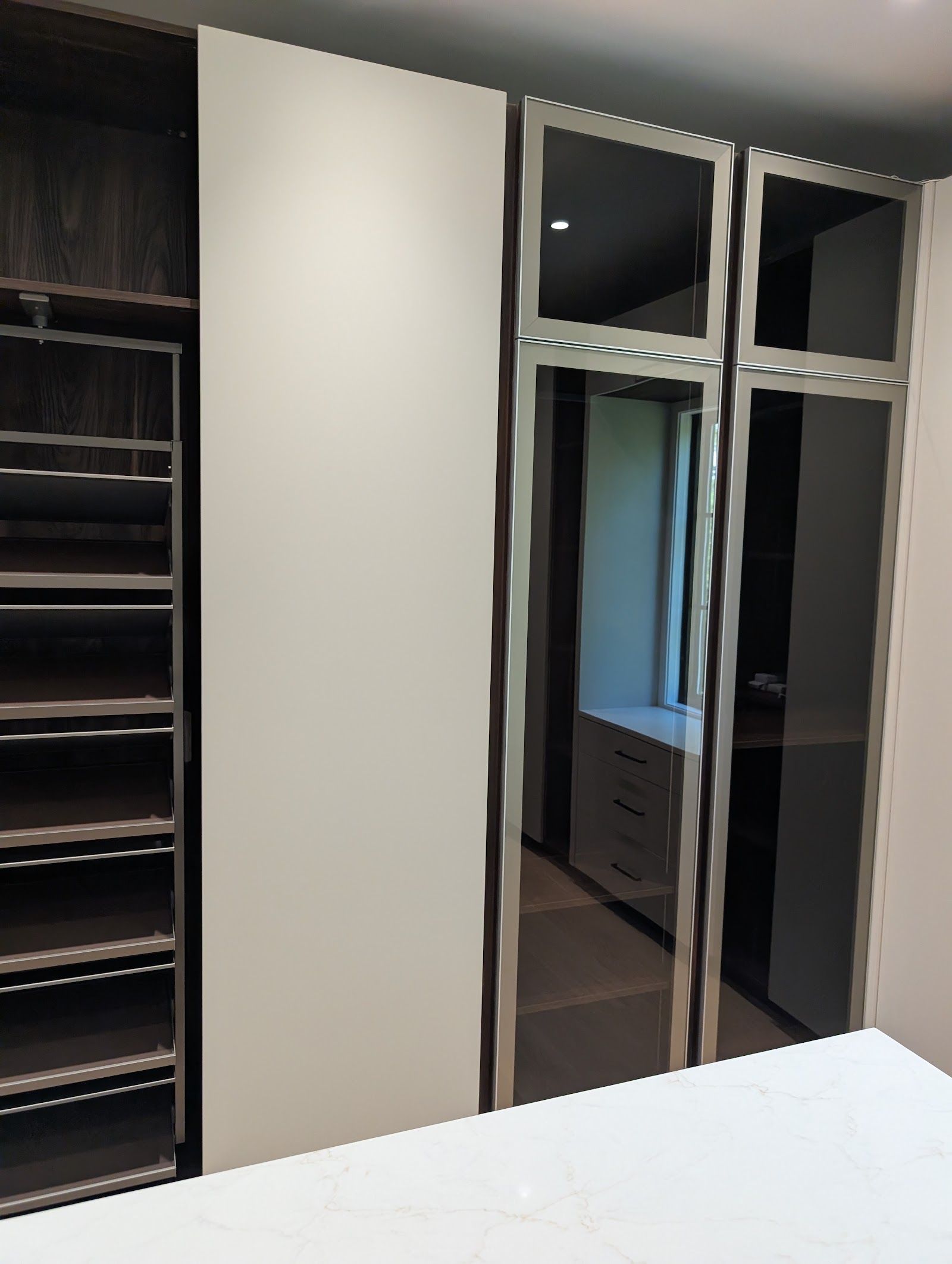Smoke-glass wardrobe doors beside a quartz-topped base cabinet